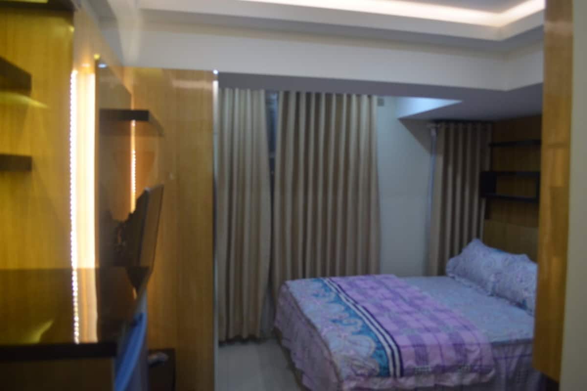 A hotel room with a bed, curtains, and a wooden desk.