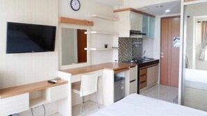 Una cocina moderna con estufa integrada, microondas y pileta. Tiene una encimera de madera y una silla blanca.