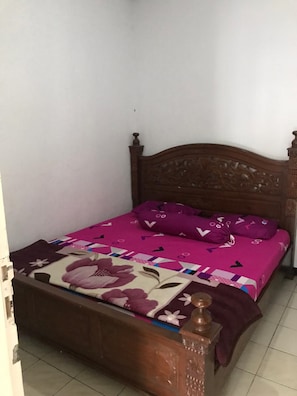 Una cama individual con cabecera de madera, cubrecama estampado floral y almohadas a juego.