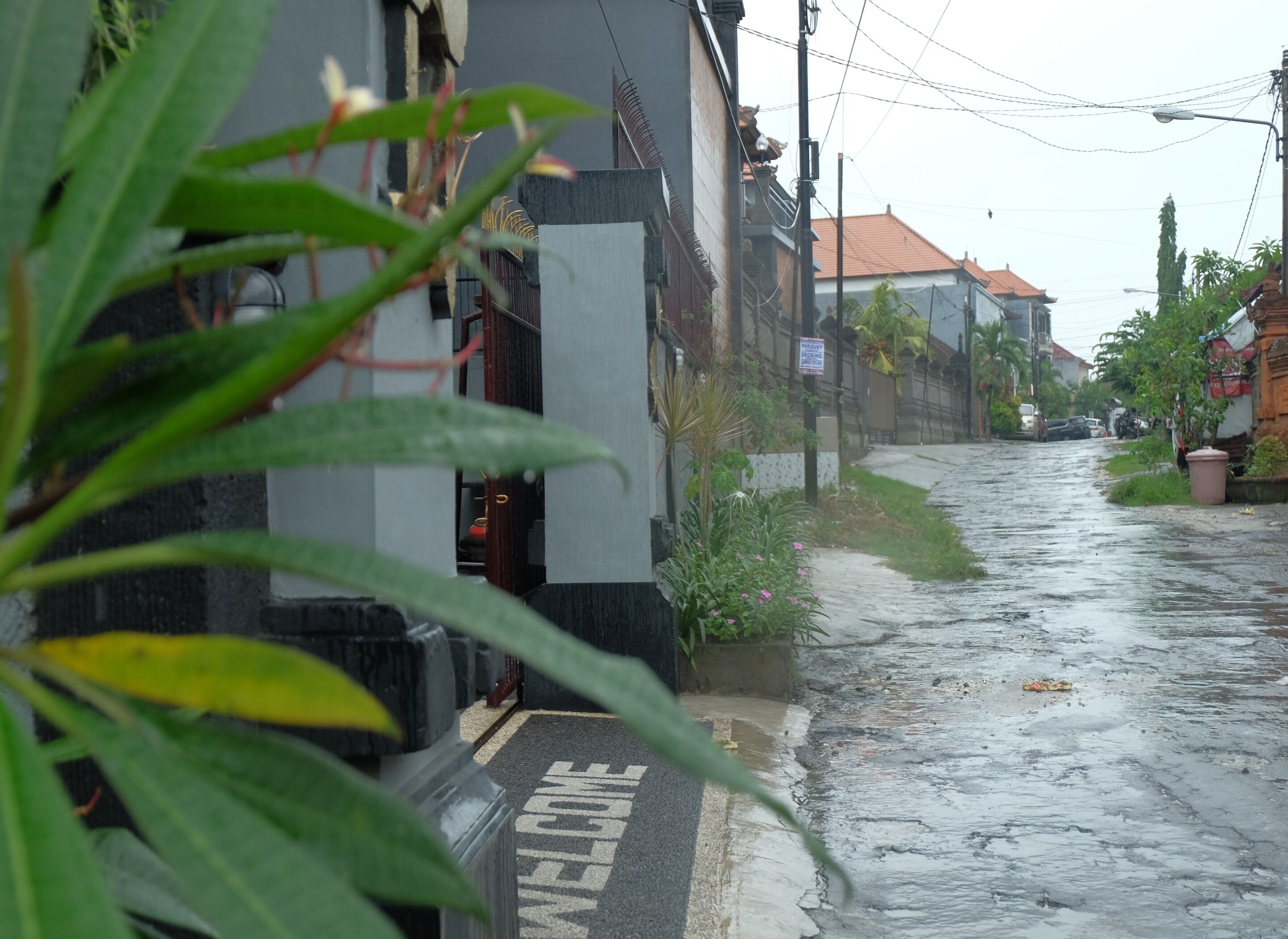 A wet street with a 'WELCOME' sign at the entrance of a building.
