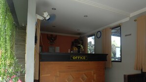 A reception desk labeled "OFFICE" with a clock and a window with curtains.