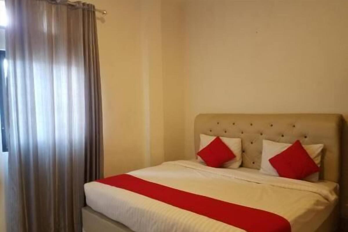 A hotel room with a bed, curtains, and a headboard.