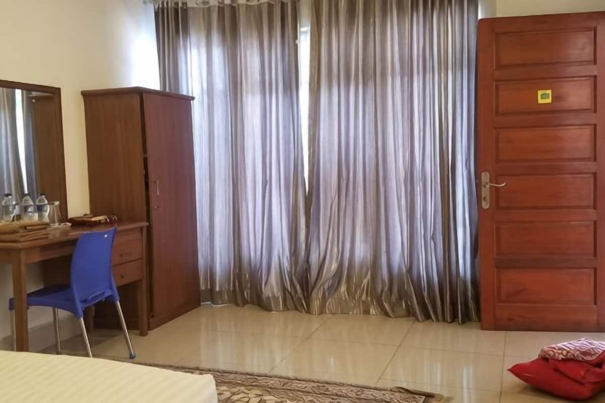 A room with a wooden desk, a chair, a wardrobe, and a door.