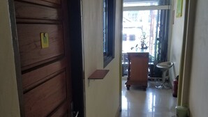 Un couloir avec une porte en bois, une petite table, une fenêtre et une vue sur l’extérieur.