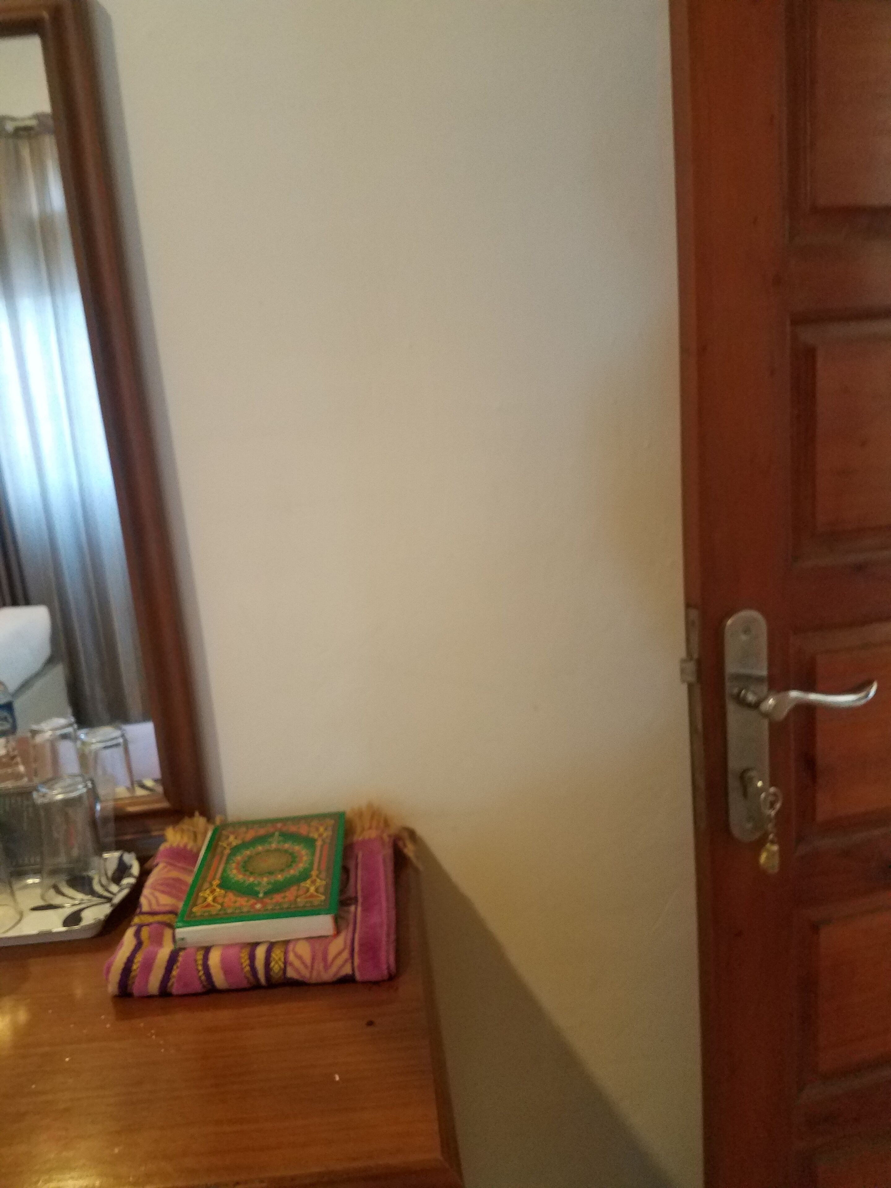 Une table en bois, ornée d’un petit objet décoratif, et un miroir accroché au mur.