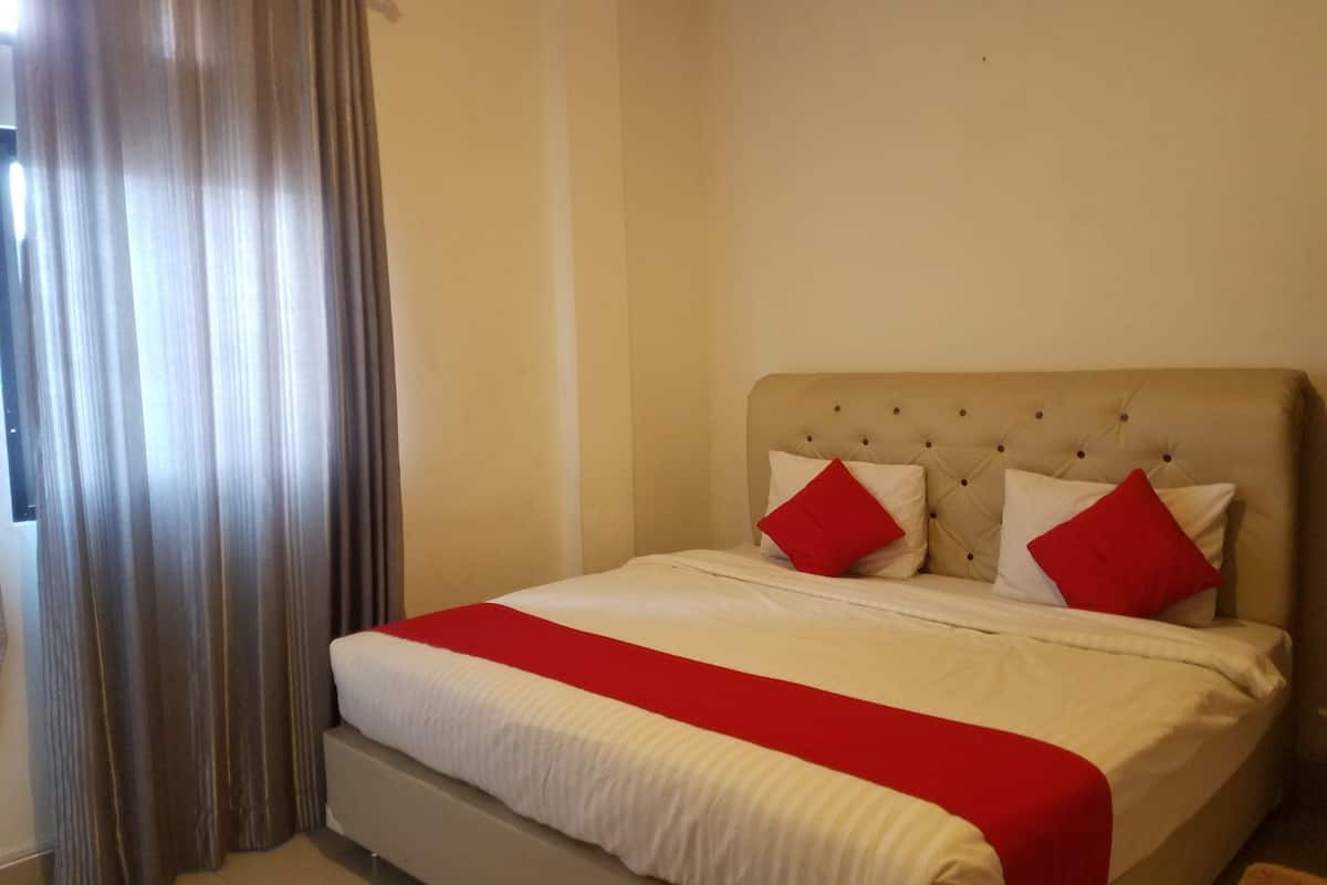A hotel room with a bed, curtains, and a headboard.