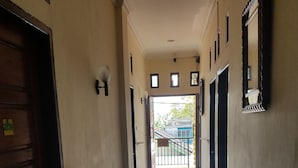 Un couloir avec une porte en bois sur la gauche, un luminaire et un miroir sur la droite.