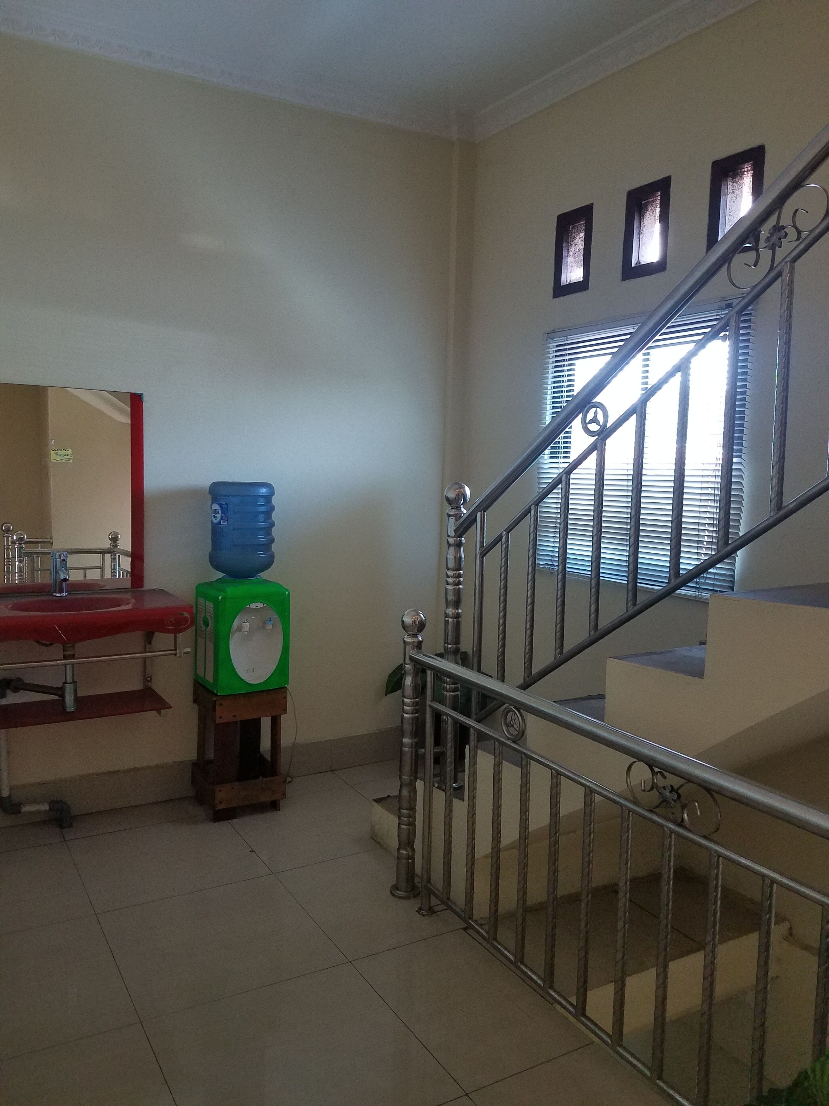 Une chambre d’hôtel avec salle de bain, un distributeur d’eau et un escalier.