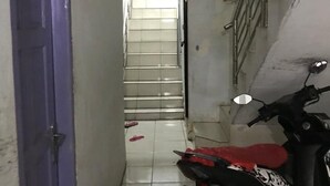 A narrow hallway with a purple door, a staircase, and a parked motorcycle. - Kost Aka (Makassar)