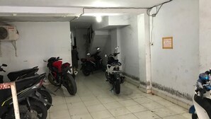 A narrow, tiled hallway with several motorcycles parked on one side. - Kost Aka (Makassar)