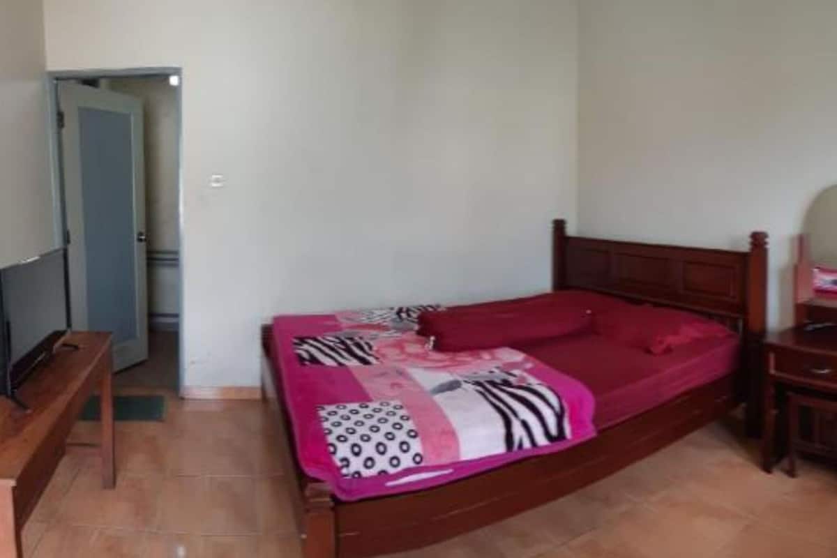 Un dormitorio con cama, cómoda, silla y ventana con cortinas.