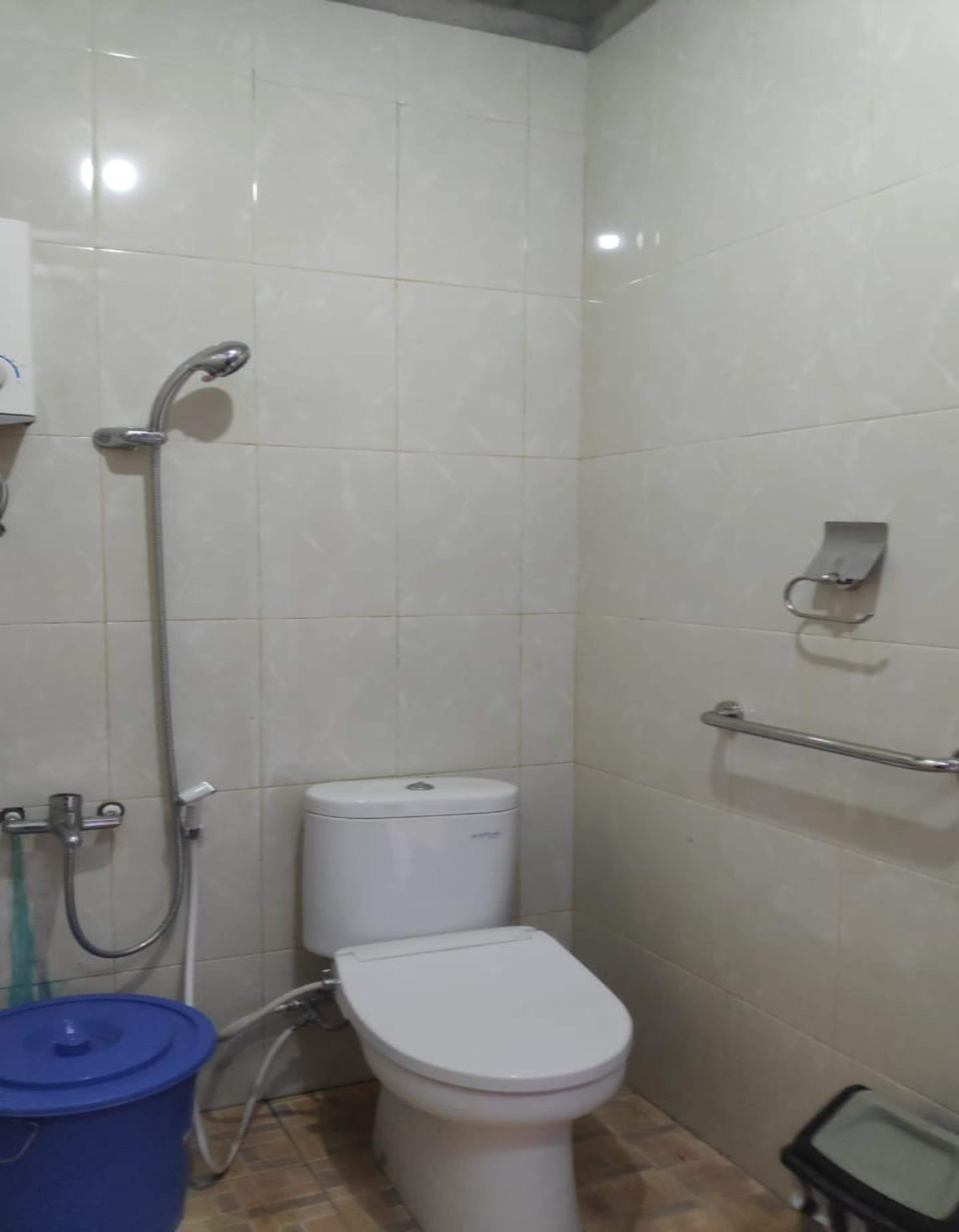 Un baño con inodoro, ducha y barra de apoyo.
