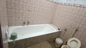 A bathroom with a bathtub, toilet, and a bucket. - Wahyu Utomo Syariah (Tawangmangu)