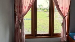 A room with a large window, curtains, and a tiled floor. - Wahyu Utomo Syariah (Tawangmangu)