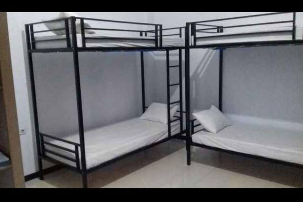 A room with two bunk beds, each with a mattress and pillow.