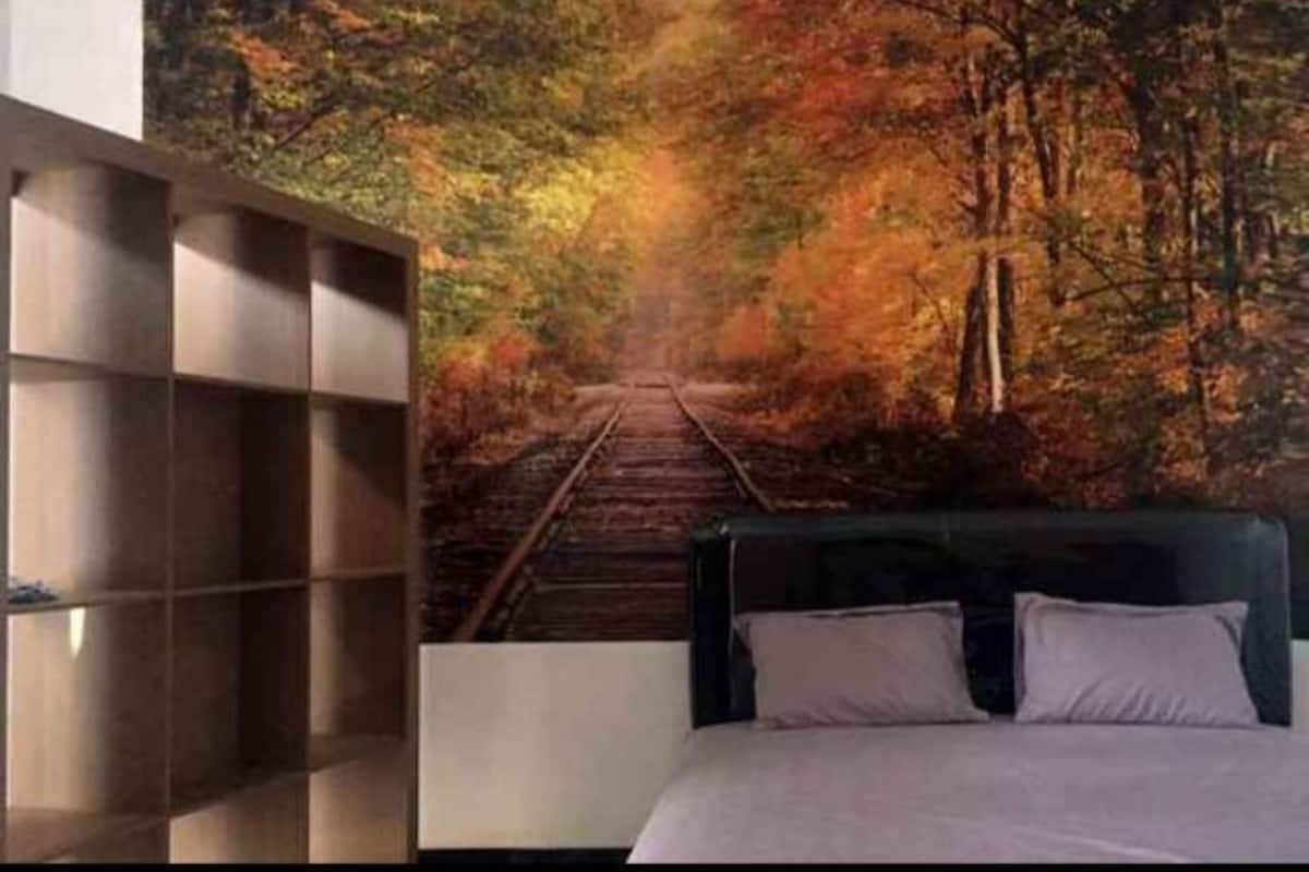 A bedroom with a bed, a headboard, and a wall with a forest scene.