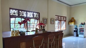 Un espace bar avec un comptoir en bois, des tabourets de bar, des objets décoratifs et des tableaux encadrés accrochés au mur.