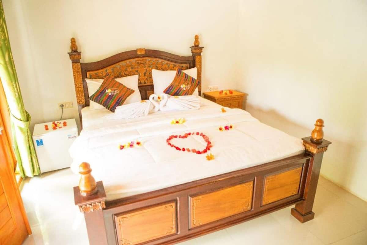 A neatly made bed with a wooden headboard, white linens, and decorative pillows.