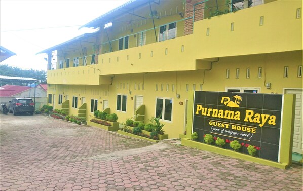 A yellow building with a sign for Purnama Raya Guest House, part of Sriwijaya Hotel. - Purnama Raya Guest House (Pematangsiantar)