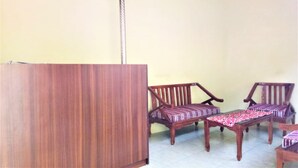 A room with a wooden desk and two wooden chairs with patterned cushions.