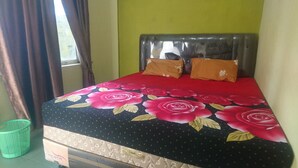 A bed with a floral bedspread, a headboard, and two pillows.