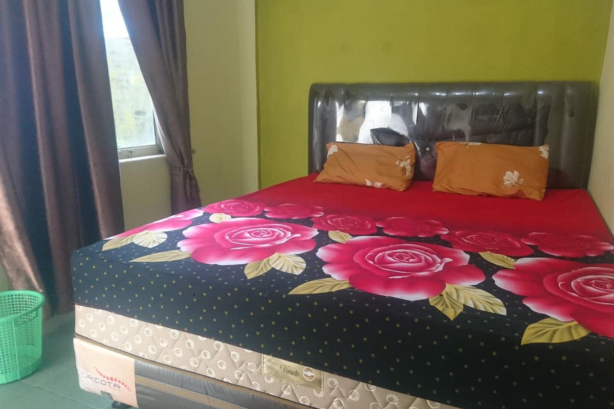 A bed with a floral bedspread, a headboard, and two pillows.