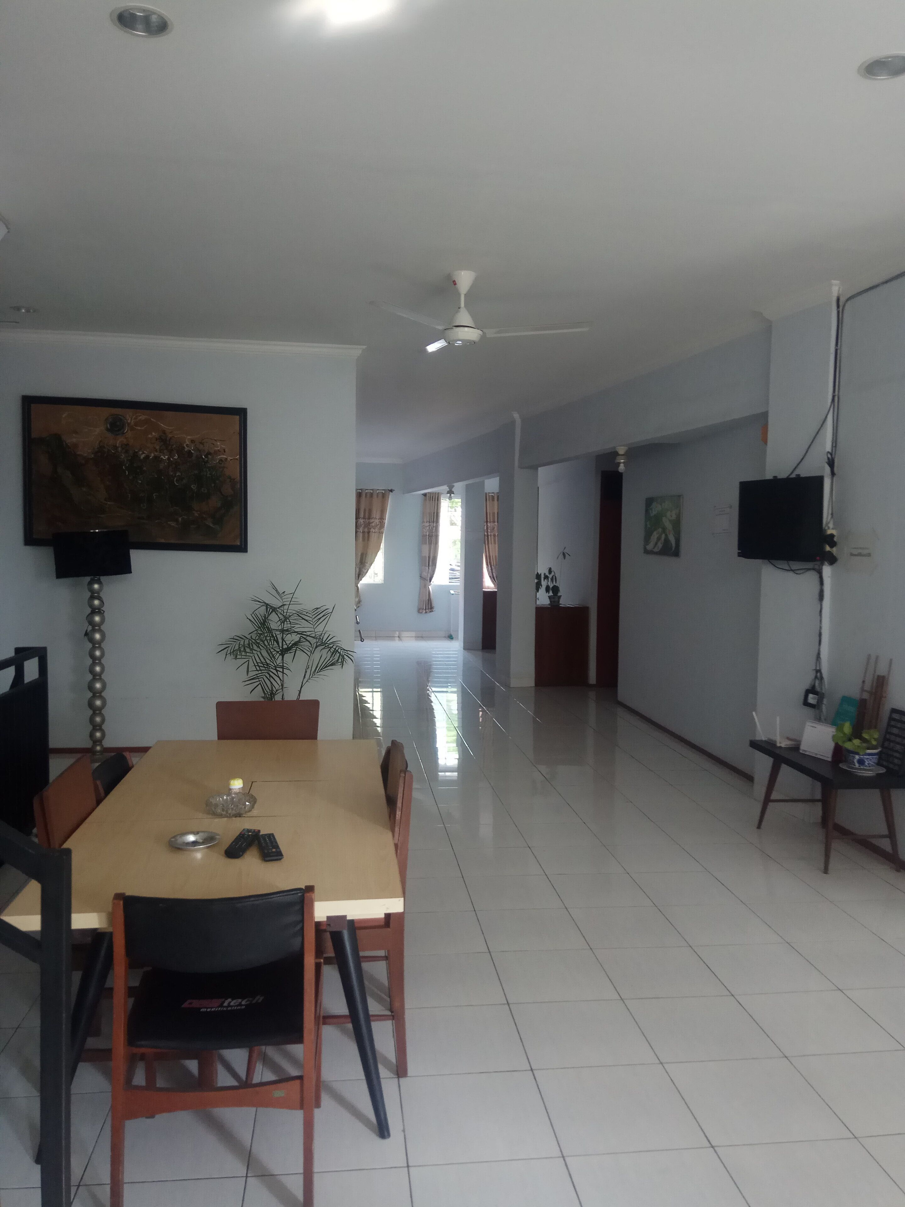 Spaziosa sala da pranzo con tavolo e sedie in legno, una ventola a soffitto e un quadro appeso al muro.