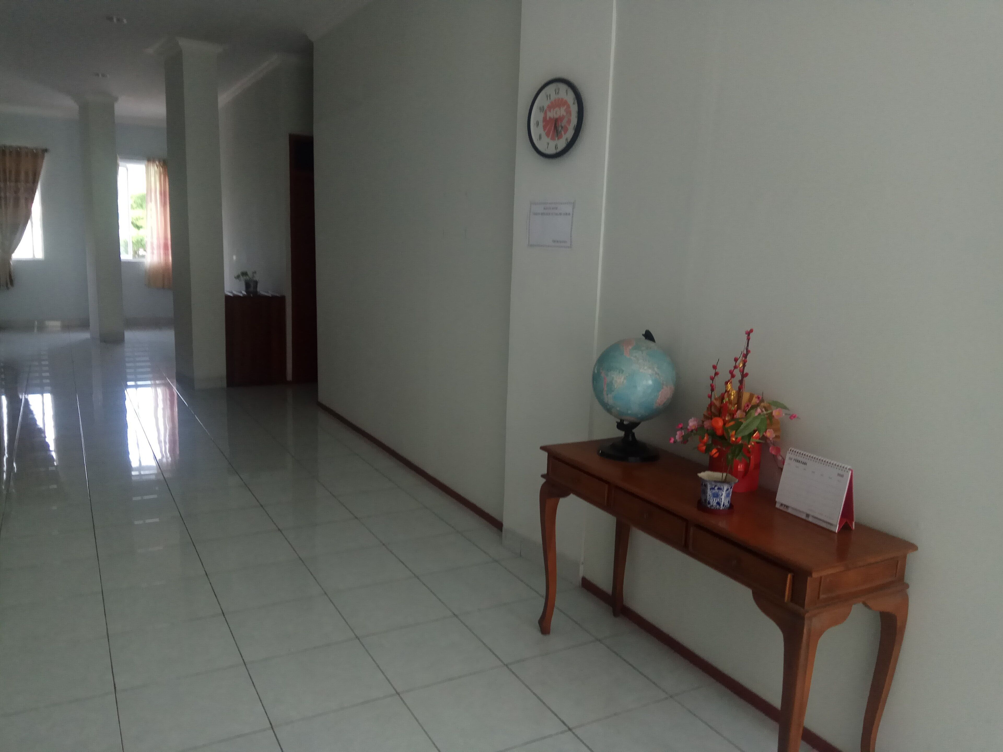 Un pasillo con un escritorio de madera, un globo terráqueo y un reloj en la pared.