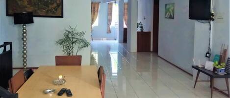 A spacious dining area with a wooden table, chairs, and a potted plant.