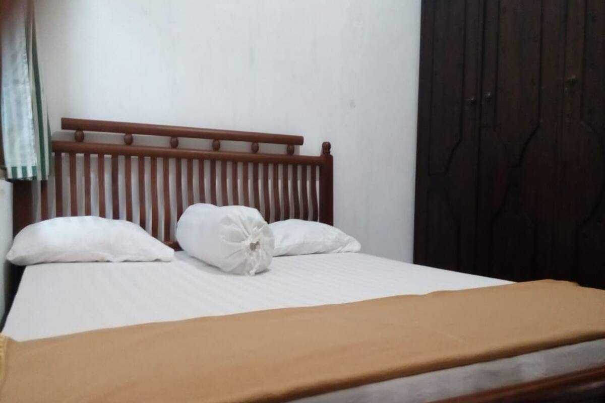 A bed with a wooden headboard, white pillows, and a brown bedspread.
