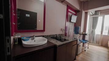 A modern kitchen with a white sink, dark cabinets, and a marble countertop.