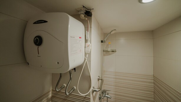 Uma casa de banho moderna com aquecedor de água embutido, um chuveiro e um secador de mãos.