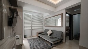 A modern living room with a grey sofa, a large mirror, and a grey rug. - The Jarrdin by Bethania Pro (Bandung)