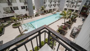 A residential building with a swimming pool surrounded by potted plants and palm trees. - The Jarrdin by Bethania Pro (Bandung)