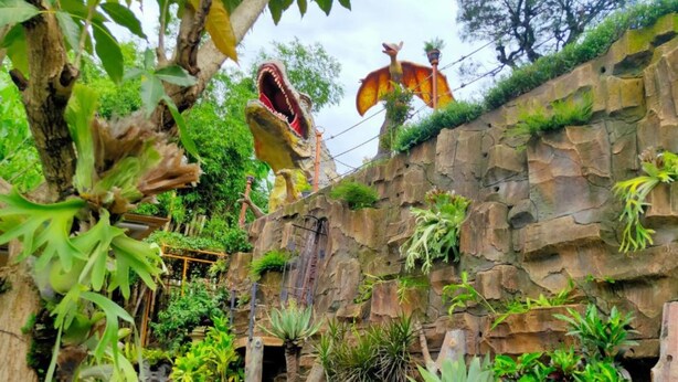 A lush indoor garden with a variety of plants, a waterfall feature, and a large dinosaur sculpture. - Anargya Guest House (Malang)
