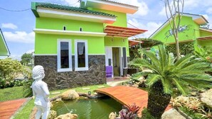 A two-story house with a stone facade and a green roof. - Anargya Guest House (Malang)