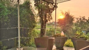 A balcony with wicker furniture, a glass table, and potted plants. - Anargya Guest House (Malang)
