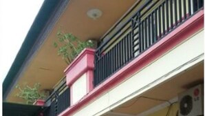 A two-story building with a balcony on the upper floor. There are multiple doors and windows on the ground floor, and a small table and chairs outside. - Griya Dua Putra Jaya I (Bojonegoro)