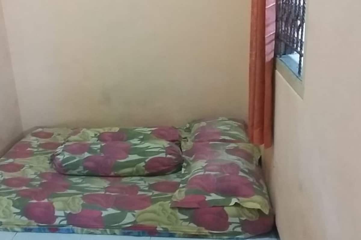 A small, enclosed room with a floral-patterned mattress and a single wall.