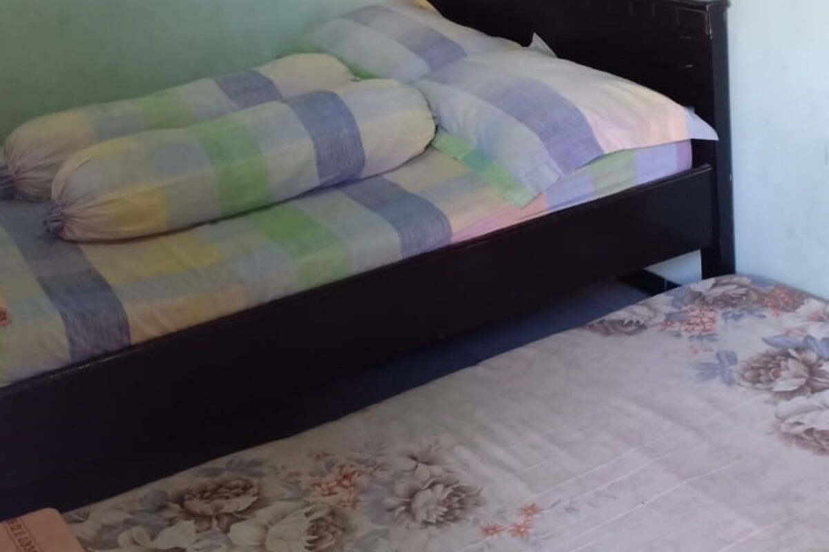 A single bed with a floral-patterned bedspread and a checkered blanket.