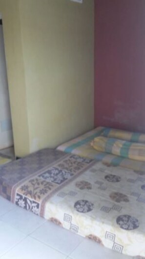 Une chambre avec un lit, une couvre-lit à motifs et un mur uni.