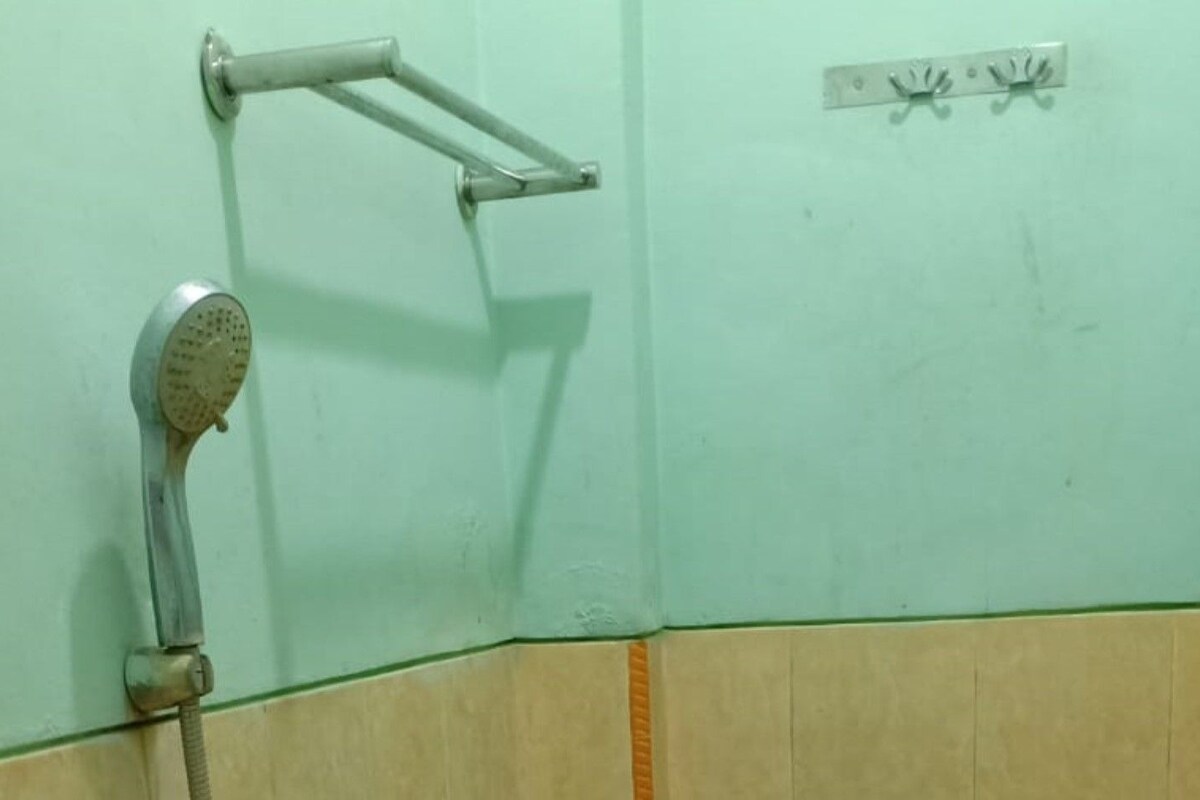 Un coin d’une salle de bain avec une pomme de douche et une barre d’appui fixée au mur.