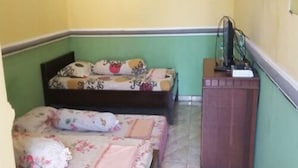 Une petite pièce avec deux lits, une armoire en bois et un téléviseur.