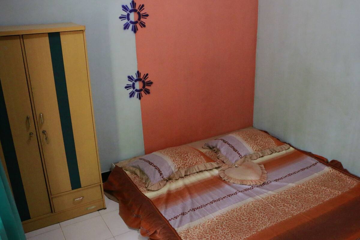 A bedroom with a bed, a wardrobe, and walls decorated with sun motifs.