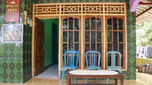 Una habitación con un separador de madera, dos sillas de plástico azul, una mesa de madera y un cartel.