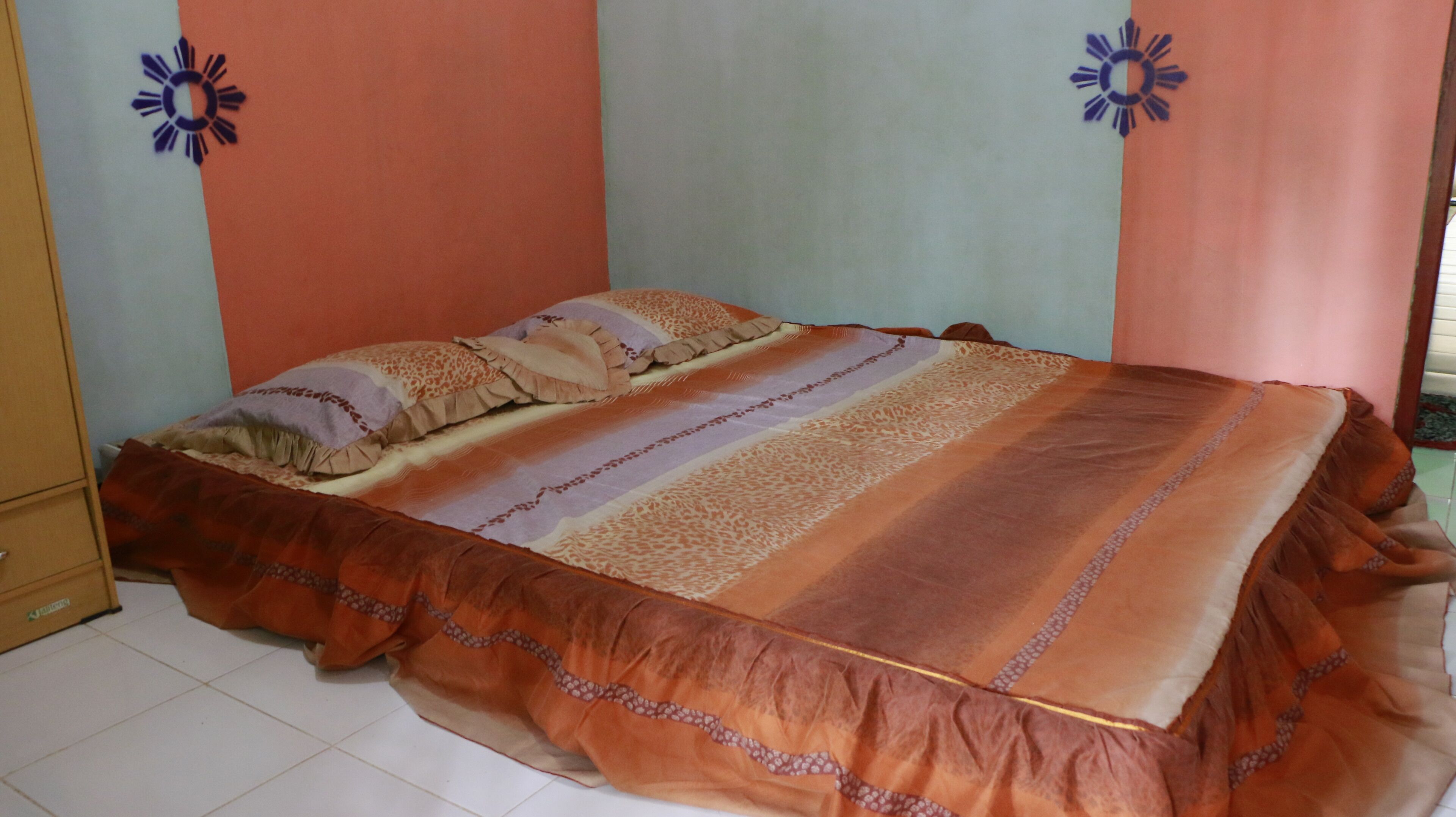 A bedroom with a bed, a dresser, and a tiled floor.
