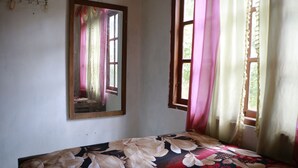 A room with a bed, a window with curtains, and a mirror on the wall. - Homestay Jemiran (Kokap)