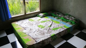 Un letto piccolo con una coperta a tema tigre, una finestra con tende blu e un pavimento a scacchi.