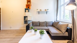 A modern living room with a sectional sofa, a white coffee table, and decorative plants. - Victus Apartamenty - Penthouse 1 (Sopot)