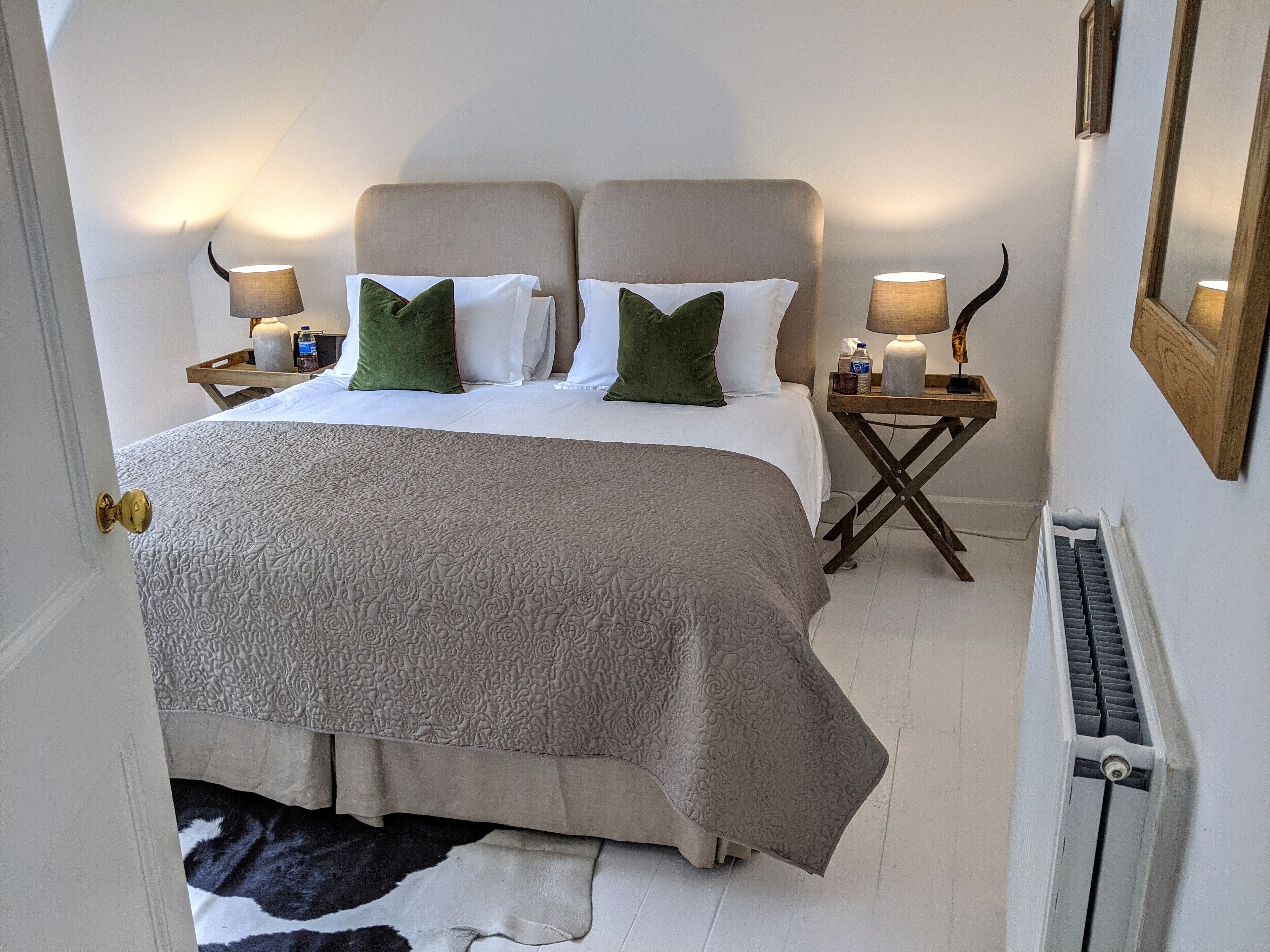 A neatly arranged bedroom with a large bed, two bedside tables, and a radiator.